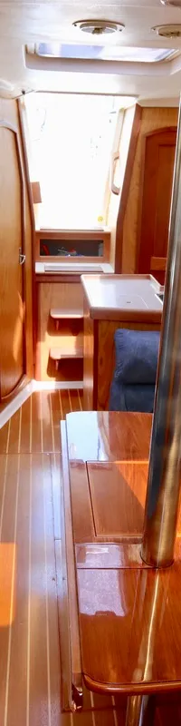 De foto toont het interieur van een boot met een houten tafel, blauwe banken, een kombuis en een navigatiehoek. — Hunter 340