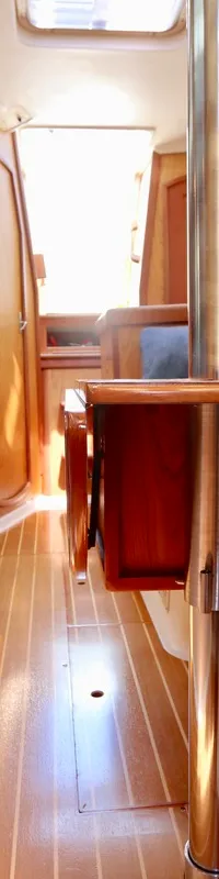 De foto toont het interieur van een boot met houten vloer, blauwe kussens en een tafel met een metalen poot. — Hunter 340