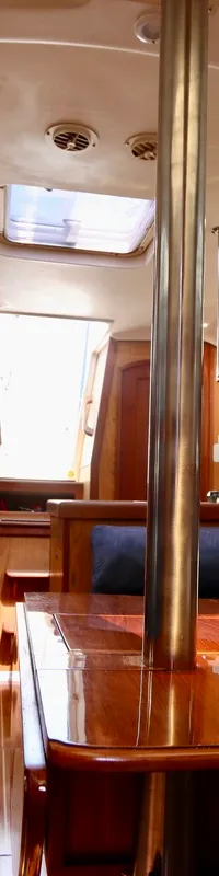De foto toont het interieur van een boot met een houten tafel, blauwe banken, ramen en een brandblusser. — Hunter 340