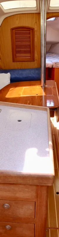 De foto toont het interieur van een boot met een kombuis, zithoeken met blauwe kussens en een houten vloer. — Hunter 340