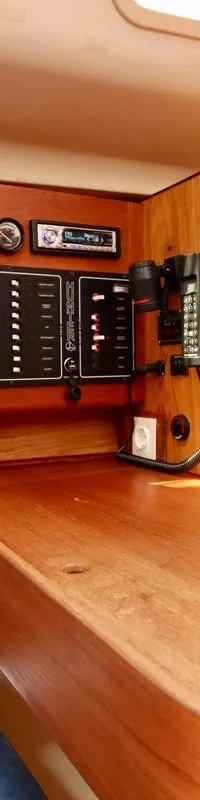 De kajuit toont een houten interieur met een blauwe bank, een bedieningspaneel, een radio en een telefoon. — Hunter 340
