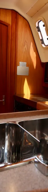 De foto toont een kombuis met twee roestvrijstalen spoelbakken, een kraan, een magnetron en houten kasten en deuren.