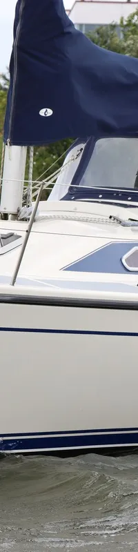 Een witte zeilboot met de naam "Calathea" in blauwe letters op de boeg, vaart op water met lichte golven.