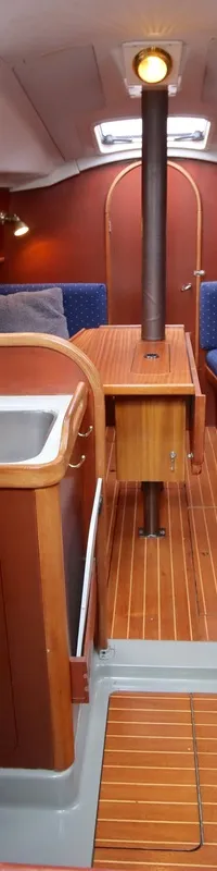 Een interieur van een boot met houten vloer, blauwe banken, een keukenblok met spoelbak en een tafel. — Dehler 34 Optima 106