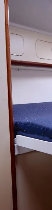 Een kajuit met een blauw matras met witte stippen, een dakraam en opbergvakken aan de zijkanten. — Dehler 34 Optima 106
