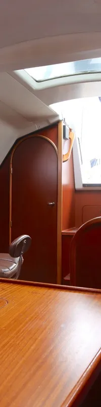 De foto toont het interieur van een boot met een houten tafel, blauwe kussens en een kleine gootsteen. — Dehler 34 Optima 106