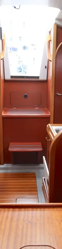 De foto toont het interieur van een boot met houten panelen, een kombuis, een navigatiehoek en slaapplaatsen.