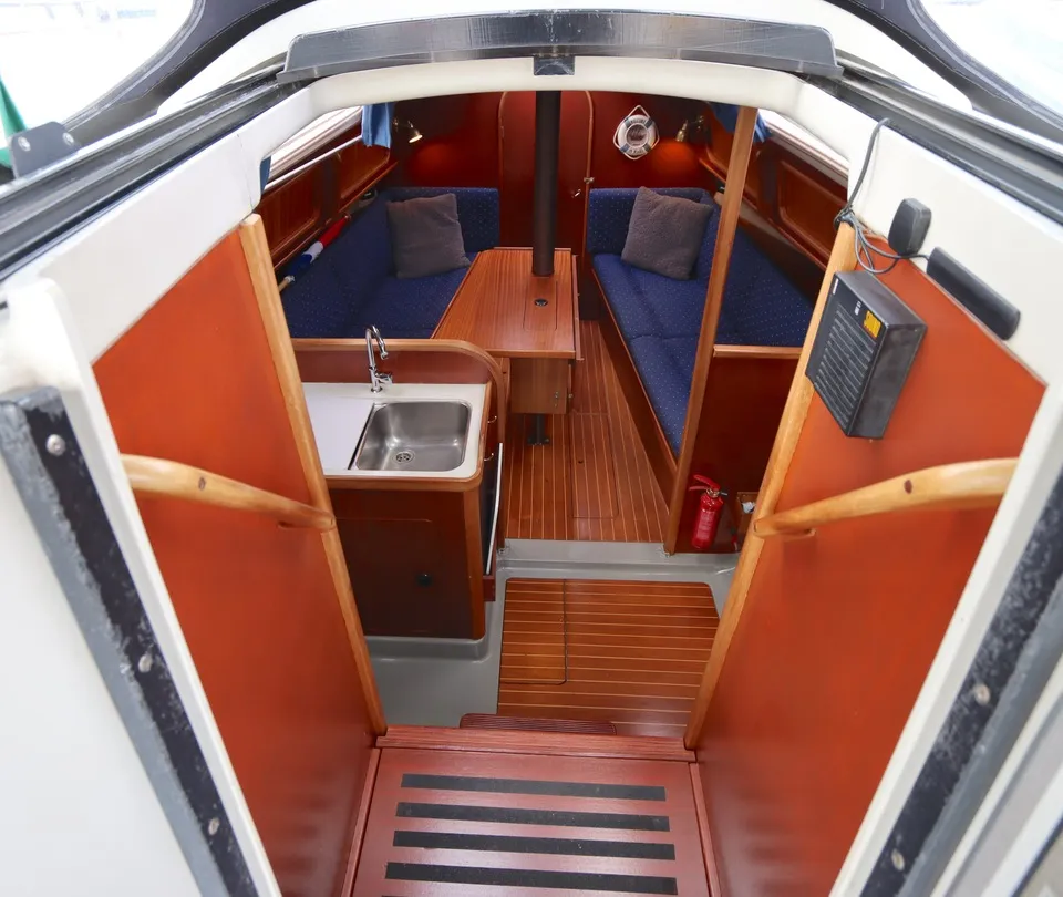 De foto toont het interieur van een boot met een kombuis, zithoek en houten vloer. — Dehler 34 Optima 106