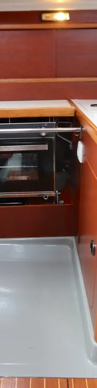 Een kombuis met een oven, een gootsteen met kraan, en houten kasten en afwerkingen.