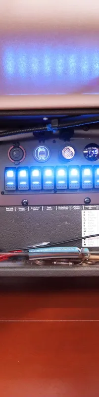 Een close-up van een bedieningspaneel met diverse elektronica, schakelaars en meters in een bootinterieur.