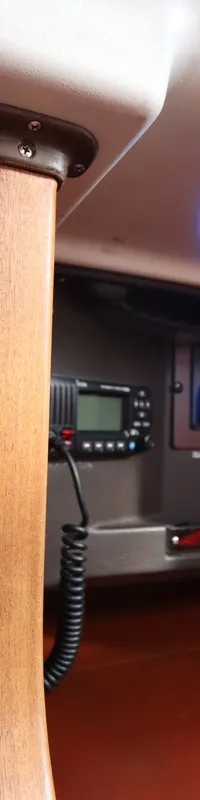 Een detailfoto van een houten interieur met een barometer, klok, marifoon en schakelpaneel.