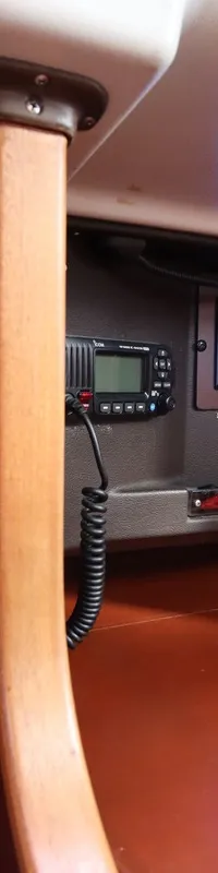 Een interieur van een boot met houten panelen, een barometer, een klok, een marifoon, een schakelpaneel en een radio.