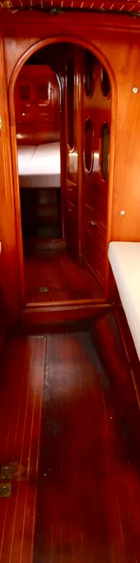 De foto toont het interieur van een boot met houten wanden en vloer, witte banken en een houten tafel. — RJ 140
