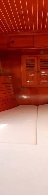 De foto toont het interieur van een kajuit met houten wanden en plafond, witte kussens en een patrijspoort. — RJ 140