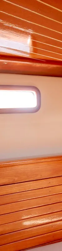 De foto toont een interieur van een boot met houten lambrisering en een klein raam. — RJ 140