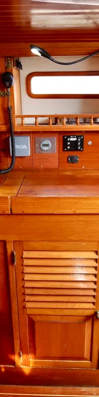 Een houten interieur van een boot met een bankje, een werkblad, diverse instrumenten en opbergkasten. — RJ 140