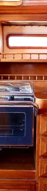 Een houten kombuis met een fornuis, oven, dubbele spoelbak en diverse kasten en lades.