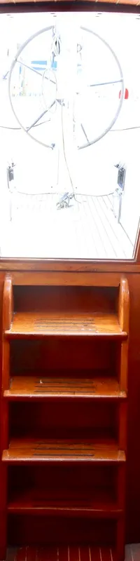 De foto toont het interieur van een boot met houten afwerking, twee slaapplaatsen en een trap naar de kuip. — RJ 140