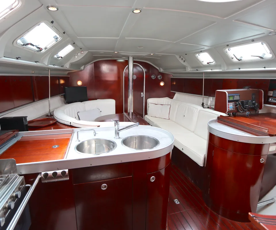 De foto toont het interieur van een boot met een kombuis, salon en navigatiehoek. — Beneteau First 41S5