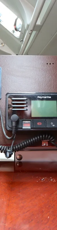 Een houten paneel met diverse navigatie- en communicatieapparatuur, waaronder een Raymarine-radio en een GPS-ontvanger.