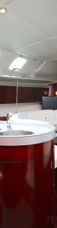 De foto toont het interieur van een boot met een kombuis, zithoek en houten vloer en wanden. — Beneteau First 41S5
