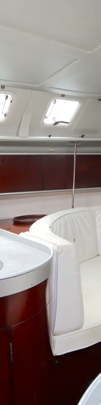 De foto toont een kajuit met een kombuis, een zithoek met witte kussens, een tafel en een televisie. — Beneteau First 41S5