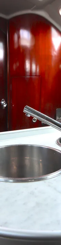 Een kombuis met een wit marmeren aanrechtblad, twee ronde roestvrijstalen spoelbakken en een chromen kraan.