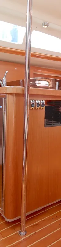 De kajuit toont een houten interieur met een kombuis voorzien van een RVS oven/fornuis, koelkast en spoelbak, en een…