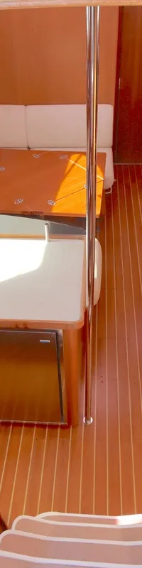 De kajuit van de boot toont een houten interieur met een kombuis, zitbanken met tafels en een trap naar beneden.
