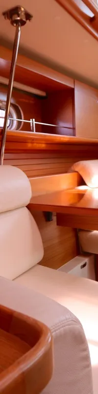 De kajuit toont een houten interieur met lichtgekleurde zitbanken, een houten tafel en een houten vloer. — Catalina 445