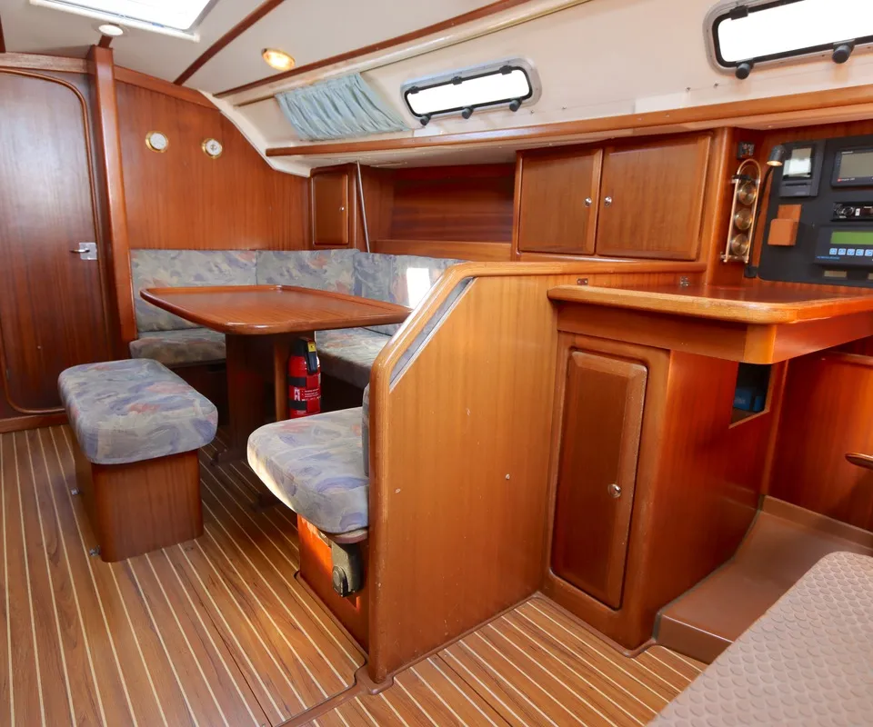 De houten kajuit toont een zithoek met tafel, een navigatiehoek en een brandblusser op de vloer. — Bavaria 35 Holiday