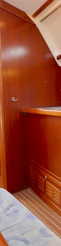 De foto toont een houten bootinterieur met een kombuis inclusief oven/fornuis, een tafel met zitbanken en een raam.