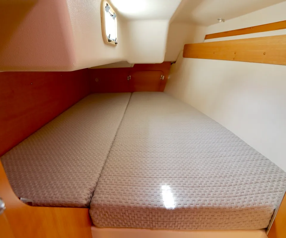 Een kajuit met een tweepersoonsbed, houten afwerking, een klein raam en een opbergplank is zichtbaar. — Etap 30i