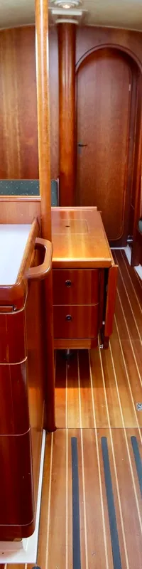 De kajuit van een boot is zichtbaar, met een houten interieur, een kombuis met dubbele spoelbak en een zithoek met groene…