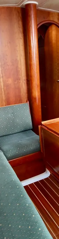 De kajuit toont een houten interieur met groene gestoffeerde banken, een houten klaptafel en een doorgang. — Winner 1120