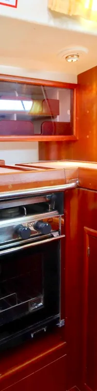 Een kombuis met een roestvrijstalen oven/fornuis, twee spoelbakken met kranen en houten kasten en panelen.