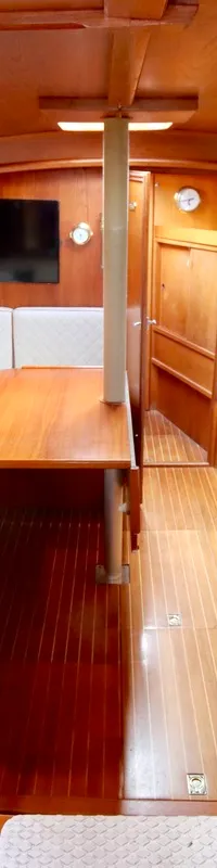 De kajuit toont een houten interieur met een zithoek, tafel, witte kussens, een televisie en een kooktoestel. — Phantom 38