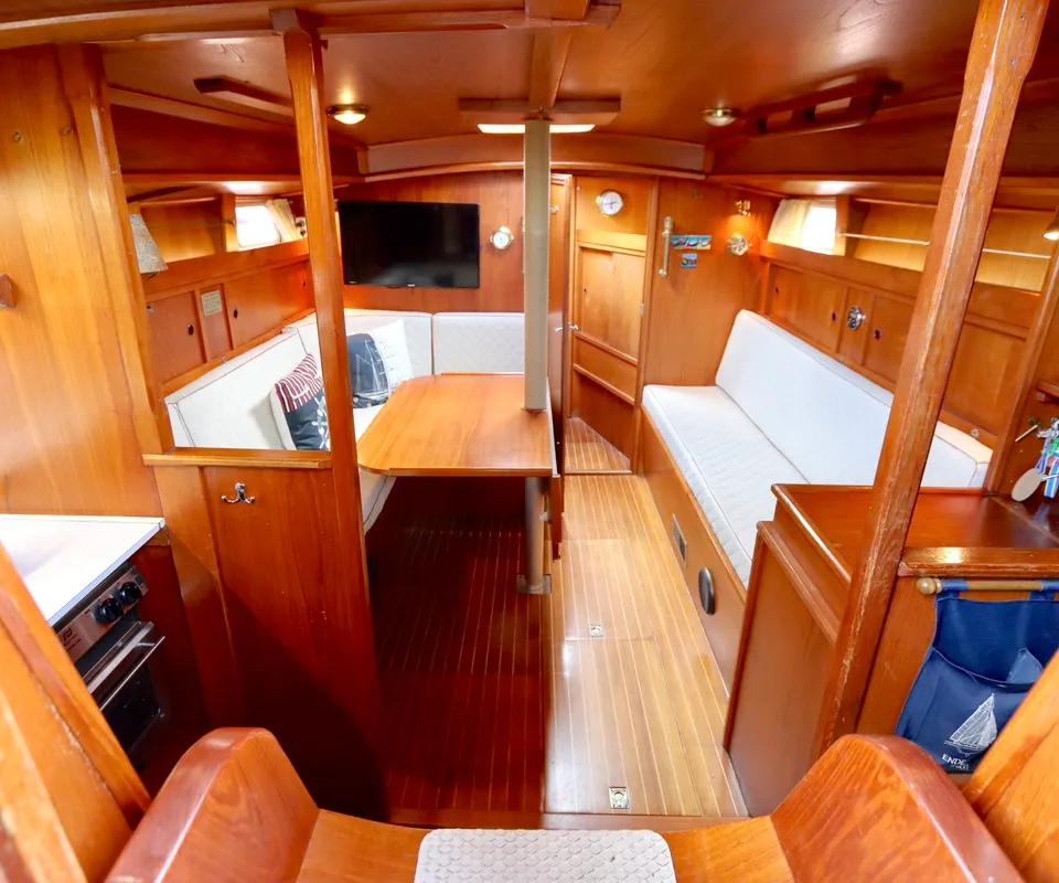 De kajuit toont een houten interieur met een zithoek, tafel, witte kussens, een televisie en een kooktoestel. — Phantom 38