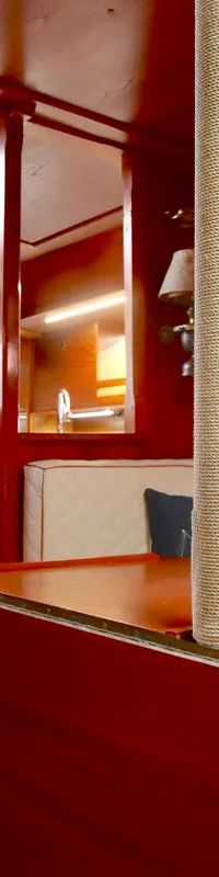De kajuit van een boot is zichtbaar, met een houten interieur, een trap, een instrumentenpaneel, een kombuis en zitbanken.