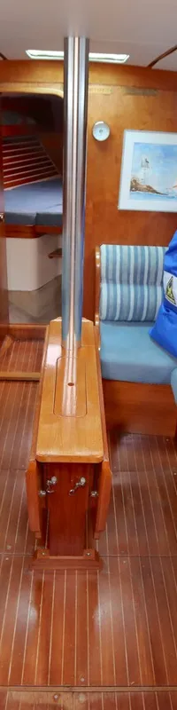De kajuit van een boot toont een houten interieur met twee banken met blauwe kussens, een gootsteen en een tafel. — Moody 376