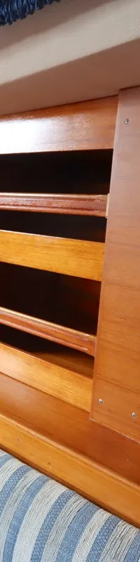 De kajuit toont een houten interieur met een bank met gestreepte kussens, opbergvakken en ramen met gordijnen. — Moody 376