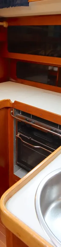 De kombuis toont een houten interieur met witte werkbladen, twee roestvrijstalen spoelbakken, een kraan en een oven.