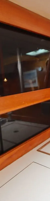 De foto toont een houten interieur met schuifdeuren van donker glas, een aanrechtblad met spoelbak en een luik.
