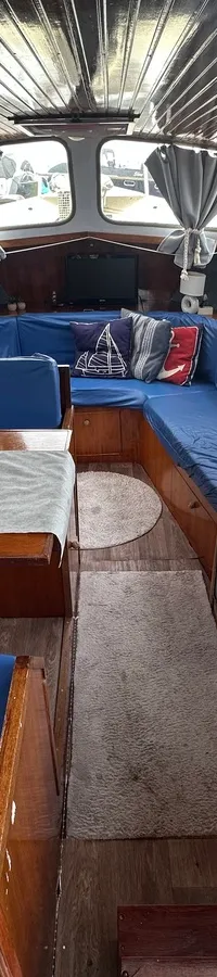 De kajuit van een boot is zichtbaar, met een kombuis aan stuurboord en een zithoek met tafel aan bakboord. — Altena GSAK