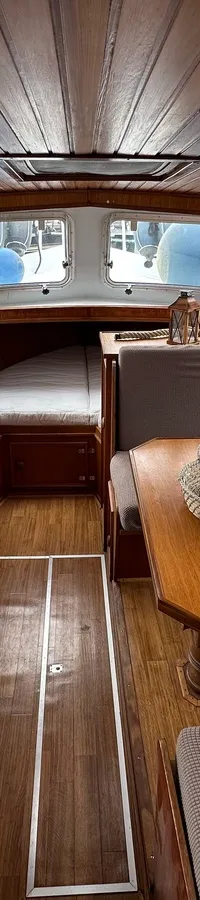 De foto toont het interieur van een boot met een houten plafond, een keukenblok en een zithoek met tafel. — Cascaruda 920