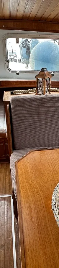 De foto toont het interieur van een boot met een houten plafond, een zithoek, een bed, een kookplaat en een koelkast.