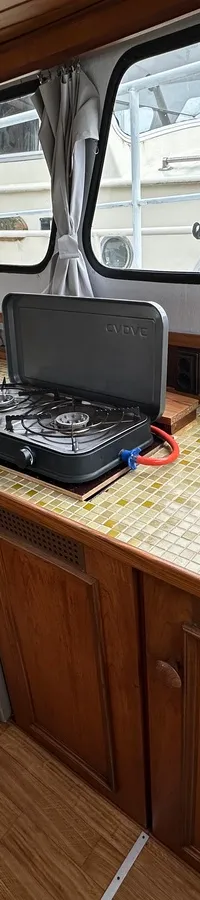 De foto toont een houten interieur van een boot met een aanrecht, gootsteen, kooktoestel en koelkast. — Cascaruda 920