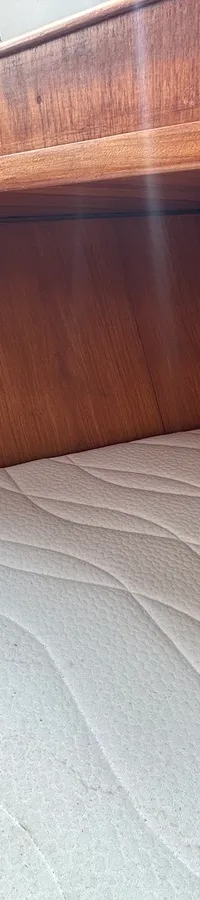 Een kajuit met een wit matras, houten wanden en een houten plank erboven. — Cascaruda 920
