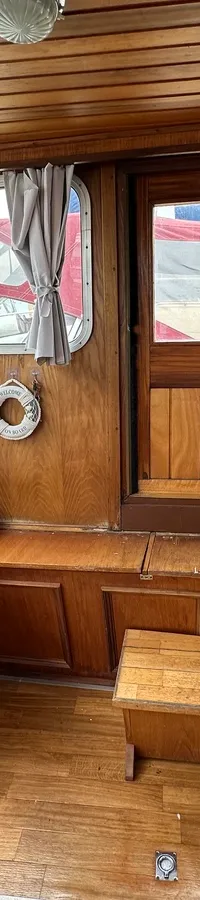 Een houten interieur van een boot met ramen, een deur, gordijnen en een klein krukje. — Cascaruda 920