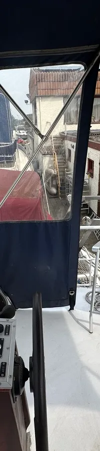 De foto toont de stuurstand van een boot met een stuurwiel, instrumentenpaneel, een Garmin-apparaat, en een reddingsboei.